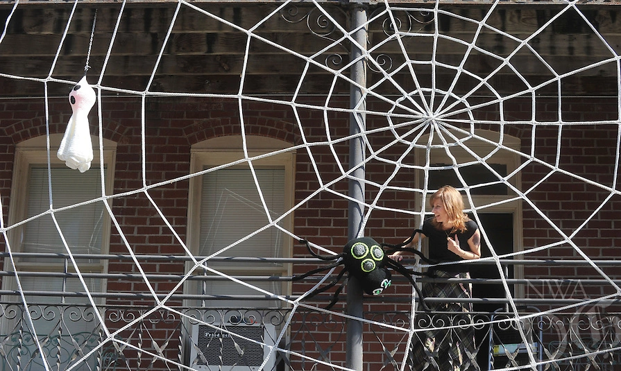 NWA Democrat-Gazette/MICHAEL WOODS • @NWAMICHAELW Gina Gallina with the Crochet Room in Eureka Springs places a crocheted spider onto a giant crocheted spiderweb on the front of the New Orleans Hotel Thursday October 8, 2015 in Eureka Springs.  Gallina spent about a week creating the web and creatures to hang on the Hotel in an effort to give it a spooky look for the Halloween season.